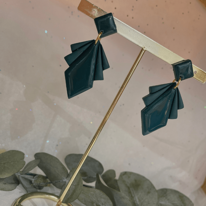 paire de boucles d'oreilles Chloé verte émeraude sur un portant à bijoux